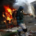 An anti-government protester sets up a barricade next to a burning kiosk during a protest at Altamira square in Caracas
