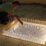 A man places a candle on a white board spelling out "MH370" during a candlelight vigil for the the missing Malaysia Airlines flight, in Kuala Lumpur