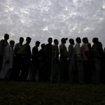 People line up to cast their vote outside a polling station in Nakhrai village in Tinsukia district