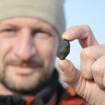 A local resident shows a fragment thought to be part of a meteorite collected in a snow covered field in the Yetkulski region outside the Urals city of Chelyabinsk