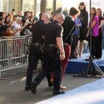 A fan is walked off carpet in handcuffs after allegedly attacking Brad Pitt