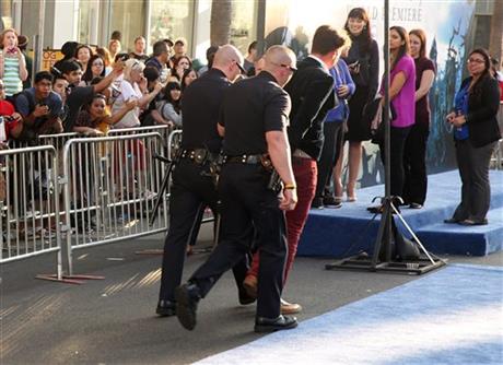 A fan is walked off carpet in handcuffs after allegedly attacking Brad Pitt