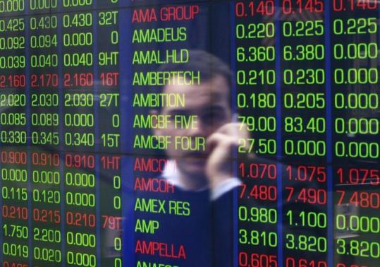 An office worker talks on his phone as he looks the stock board at the Australian Securities Exchange building in Sydney