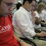 Google employees work on their laptops at Google