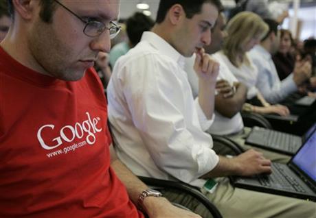 Google employees work on their laptops at Google