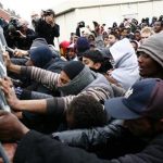 Migrants and activists scuffle with police officers