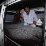 Mohammad Iqbal sits next to his wife Farzana's body, who was killed by family members, in an ambulance outside of a morgue in Lahore