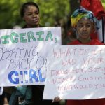 Protesters hold signs during a march in support of girls kidnapped in front of the Nigerian Embassy in Washington