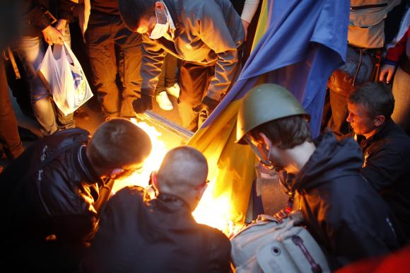 Pro-Russia protesters burn a Ukranian flag outside the district council building in Donetsk