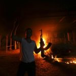 A protester reacts as the U.S. Consulate in Benghazi is seen in flames