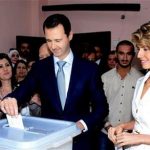 Bashar Assad, center, casts his vote as Syrian first lady Asma Assad, right,