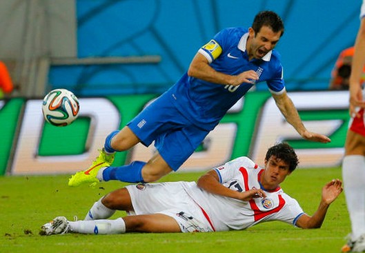Costa Rica's Yeltsin Tejeda (bottom) fouls Greece's Giorgos Karagounis