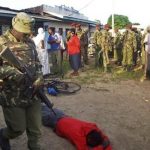Kenya, A member of the Kenyan security forces walks past the body of one of those who were killed
