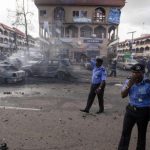 Policemen walk towards burnt vehicles at the scene of a blast at a business district in Abuja