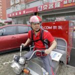 Liu, CEO and founder of China's e-commerce company JD.com, rides an electric tricycle as he leaves a delivery station in Beijing