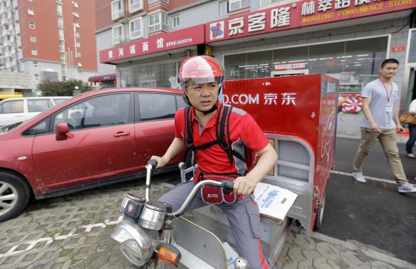 Liu, CEO and founder of China's e-commerce company JD.com, rides an electric tricycle as he leaves a delivery station in Beijing