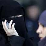 A women , wearing a niqab despite a nationwide ban on the Islamic face veil, gives a phone call outside the courts in Meaux