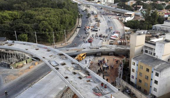 Rescue workers try to reach vehicles trapped underneath a bridge that collapsed while under construction in Belo Horizonte