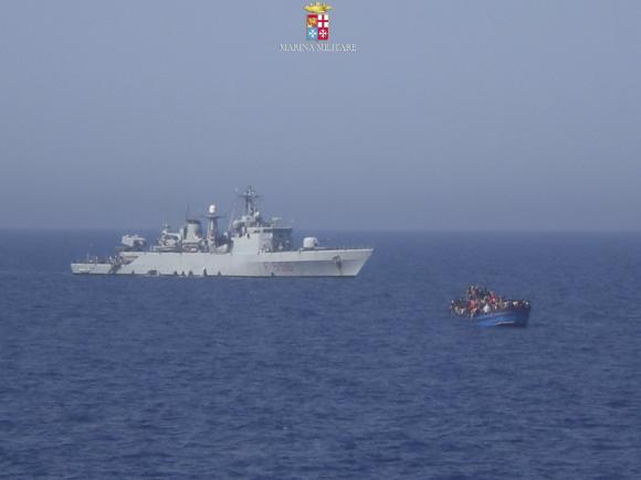 Migrants sit in their boat during a rescue operation by Italian navy ship Grecale off the coast of Sicily