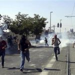 Palestinians run away from tear gas as they clash with Israeli security forces