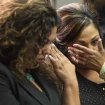 Family members of GM crash victims wipe their eyes as Kenneth Feinberg, a victims compensation lawyer hired by GM, speaks in Washington