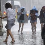Women walk amid strong winds on a street in Naha, Okinawa