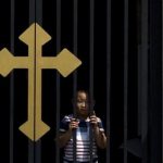 A child peers out near a cross on a gate of the Wangfujing Catholic Church in Beijing