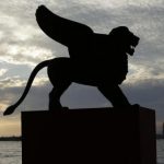 A statue of a lion, the symbol of the 69th Venice Film Festival, is silhouetted in Venice