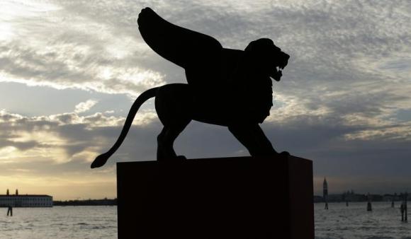 A statue of a lion, the symbol of the 69th Venice Film Festival, is silhouetted in Venice