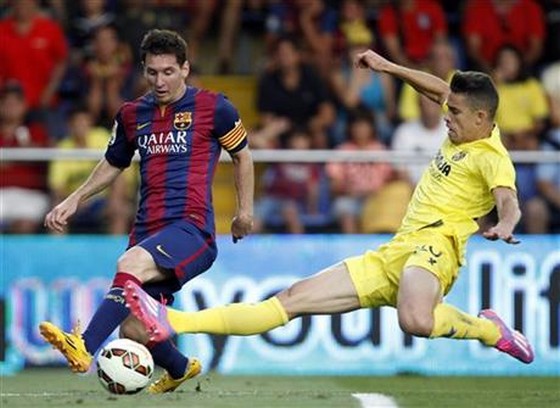 Barcelona's Lionel Messi, from Argentina, challenges for the ball with Villarreal's Grabiel Paulista