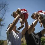 Jason Howe and Adrian Perez hold their twin daughters Clara and Olivia at a playground in West Hollywood