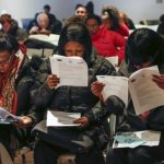 People fill out application forms before a screening session for seasonal jobs at Coney Island in the Brooklyn borough of New York