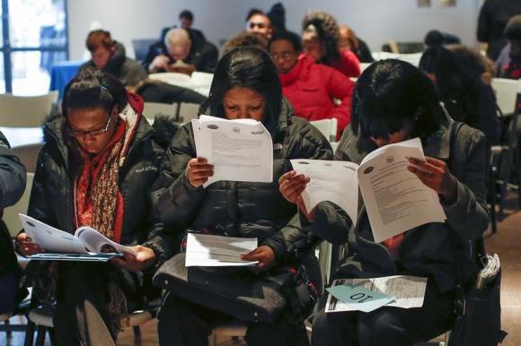 People fill out application forms before a screening session for seasonal jobs at Coney Island in the Brooklyn borough of New York