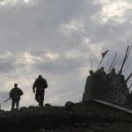 Pro-Russian separatists walk at a destroyed war memorial on Savur-Mohyla, a hill east of the city of Donetsk
