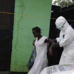 Health worker brings a woman suspected of having contracted the Ebola virus to an ambulance in Monrovia