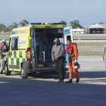 A migrant is helped by an Armed Forces of Malta (AFM) airman to a waiting ambulance after being brought to Malta by helicopter at the Air Wing base outside Valletta