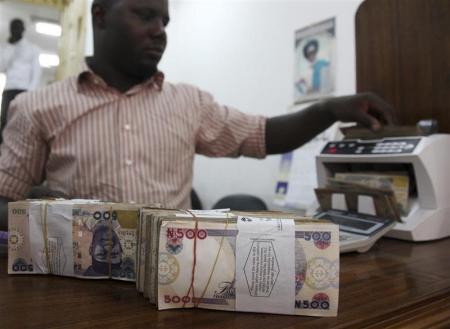 A money dealer counts the Nigerian naira on a machine in his office in the commercial capital of Lagos