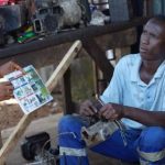 A social mobilizer from NGO (AJCOM), uses an illustrated printout while speaking with a man about Ebola and best practices to help prevent its spread in Conakry