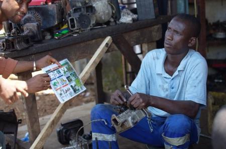 A social mobilizer from NGO (AJCOM), uses an illustrated printout while speaking with a man about Ebola and best practices to help prevent its spread in Conakry