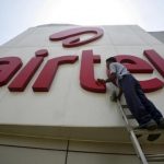 A worker cleans a logo of Bharti Airtel at its zonal office building in the northern Indian city of Chandigarh