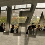 Journalists are reflected in a logo at the FIFA headquarters in Zurich