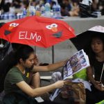 Protesters sit under umbrellas as they block the main street to the financial Central district outside the government headquarters in Hong Kong