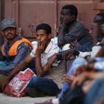 Rescued migrants sit on the ground at the Armed Forces of Malta Maritime Squadron base at Haywharf in Valletta's Marsamxett Harbour