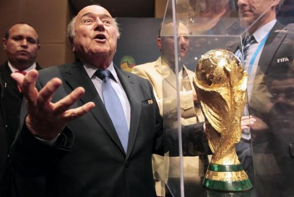 FIFA President Sepp Blatter gestures next to the World Cup trophy after a media conference in Sao Paulo