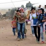 Syrian Kurds walk after crossing into Turkey at the Turkish-Syrian border, near the southeastern town of Suruc in Sanliurfa province