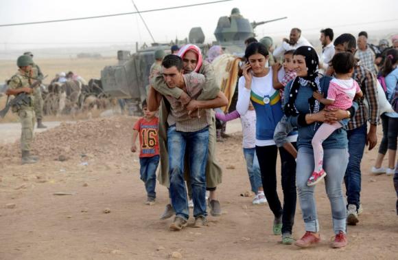 Syrian Kurds walk after crossing into Turkey at the Turkish-Syrian border, near the southeastern town of Suruc in Sanliurfa province