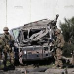 U.S. troops keep watch near a damaged vehicle at the site of suicide attack in Kabul