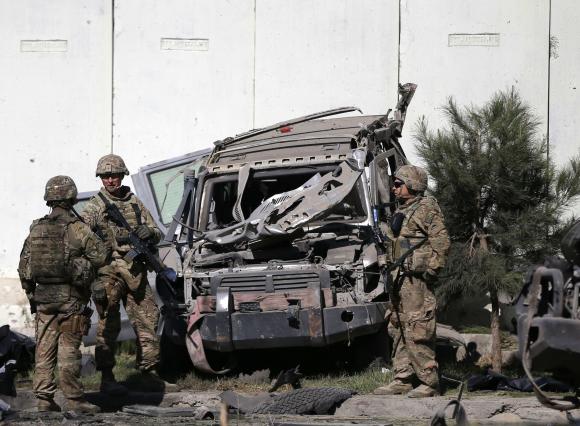 U.S. troops keep watch near a damaged vehicle at the site of suicide attack in Kabul