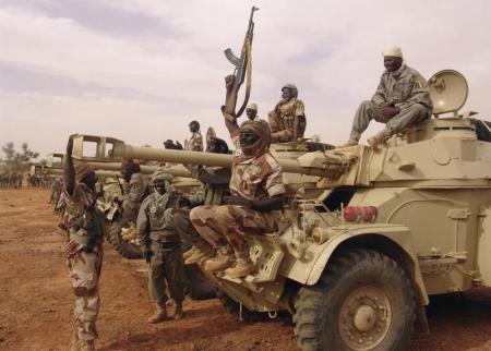 Chadian soldier sitting on a tank, holds up his weapon ahead of his deployment in Mali, at the town of Gorou, in Niger