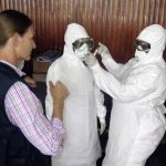 World Health Organization health worker teaches trainee health workers how to put on a protective suit in Freetown